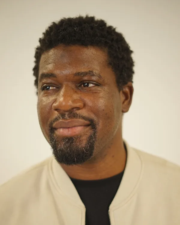 Alleo Gordon, smiling, in a cream jacket and black T-shirt